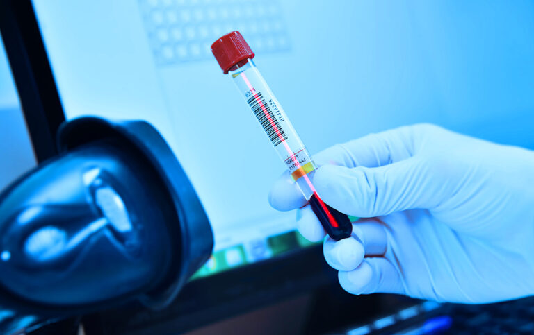 Lab test tube getting scanned by gloved hand