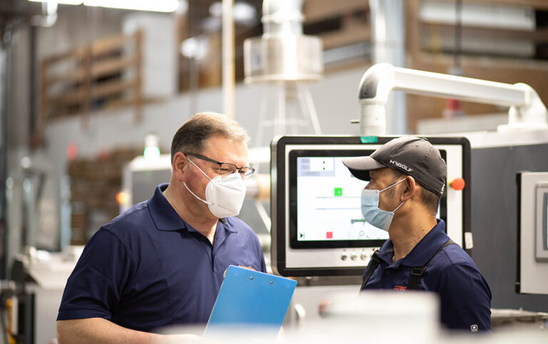 Two men in a warehouse talking to each other